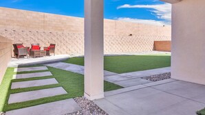A patio area with outdoor furniture, a grassy lawn, and a brick wall. - Modern Rio Rancho - Fireplace, Private Yard (Rio Rancho)