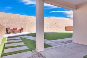 A patio area with outdoor furniture, a grassy lawn, and a brick wall. - Modern Rio Rancho - Fireplace, Private Yard (Rio Rancho)