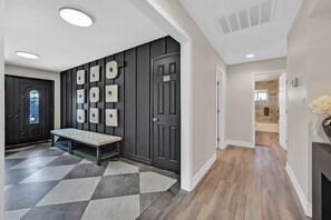 A hallway with a bench, a door with a sign, and a wall with decorative panels. - 5,000 sqft Vegas Getaway w Private Pool Near Strip (Las Vegas)