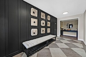 Ein moderner Flur mit einer Bank, einem Spiegel und an Wänden befestigten Holzskulpturen.
