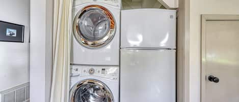 Een kleine wasruimte met twee gestapelde wasmachines en een koelkast.