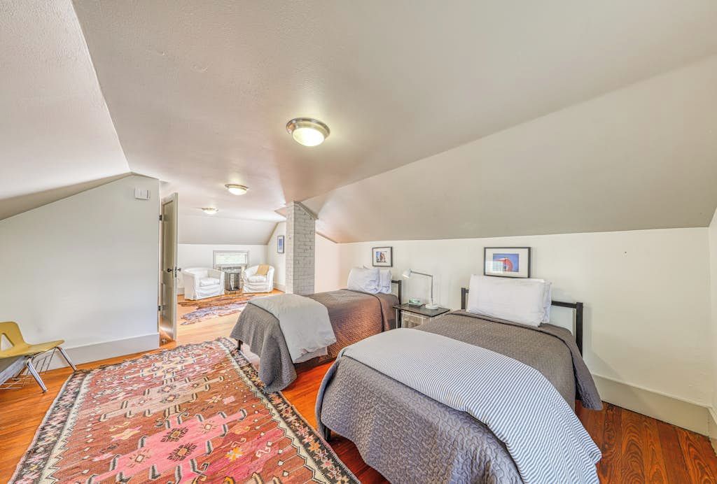 A bedroom with two beds, a patterned rug, and a small desk with a chair.