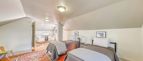 A bedroom with two beds, a patterned rug, and a small desk with a chair.