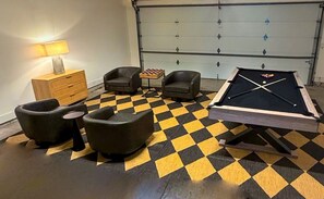 A pool table with four chairs, a small table with a chessboard, and a lamp. - 12-Bed Luxury Escape w/ Hot Tub & Rooftop (Nashville)