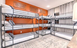 A room with bunk beds, orange walls, and patterned rugs. - 12-Bed Luxury Escape w/ Hot Tub & Rooftop (Nashville)