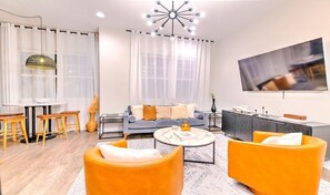 Ein modernes Wohnzimmer mit einer Couch, einem Couchtisch und orangefarbenen Sessel.