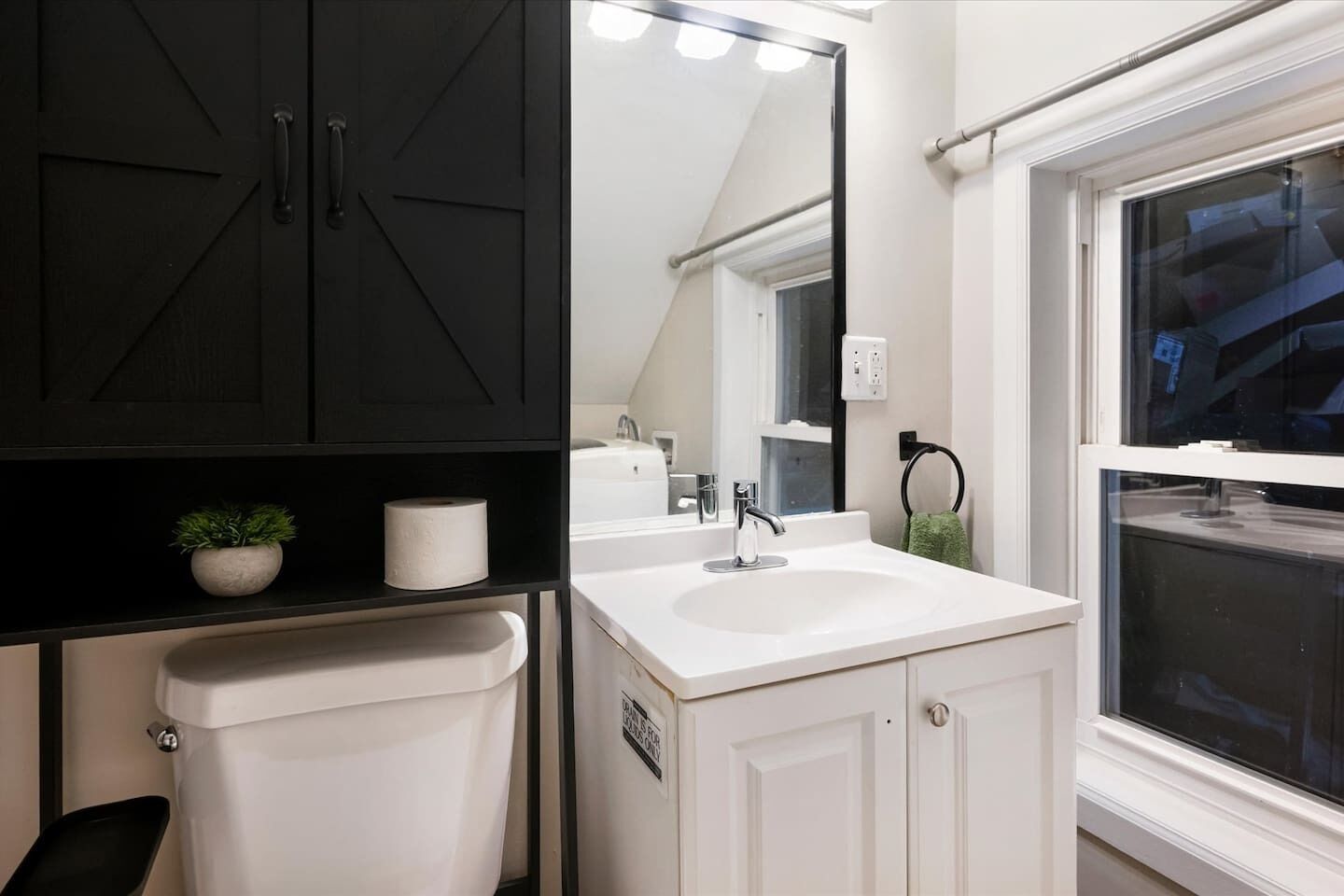 A bathroom with a toilet, sink, mirror, and a towel rack.