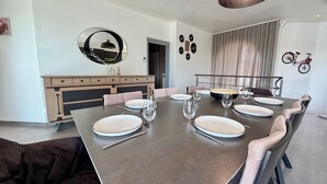 A dining area with a large table set for six, a modern pendant light, and a bicycle mounted on the wall.