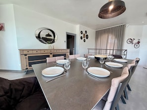 A dining area with a large table set for six, a modern pendant light, and a bicycle mounted on the wall.