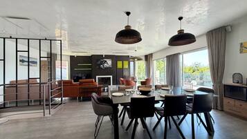 Een moderne eetruimte met een centrale tafel, stoelen en hanglampen.