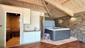 Een moderne badkamer met een houten plafond, een stenen muur, een whirlpool en een houten vloer.