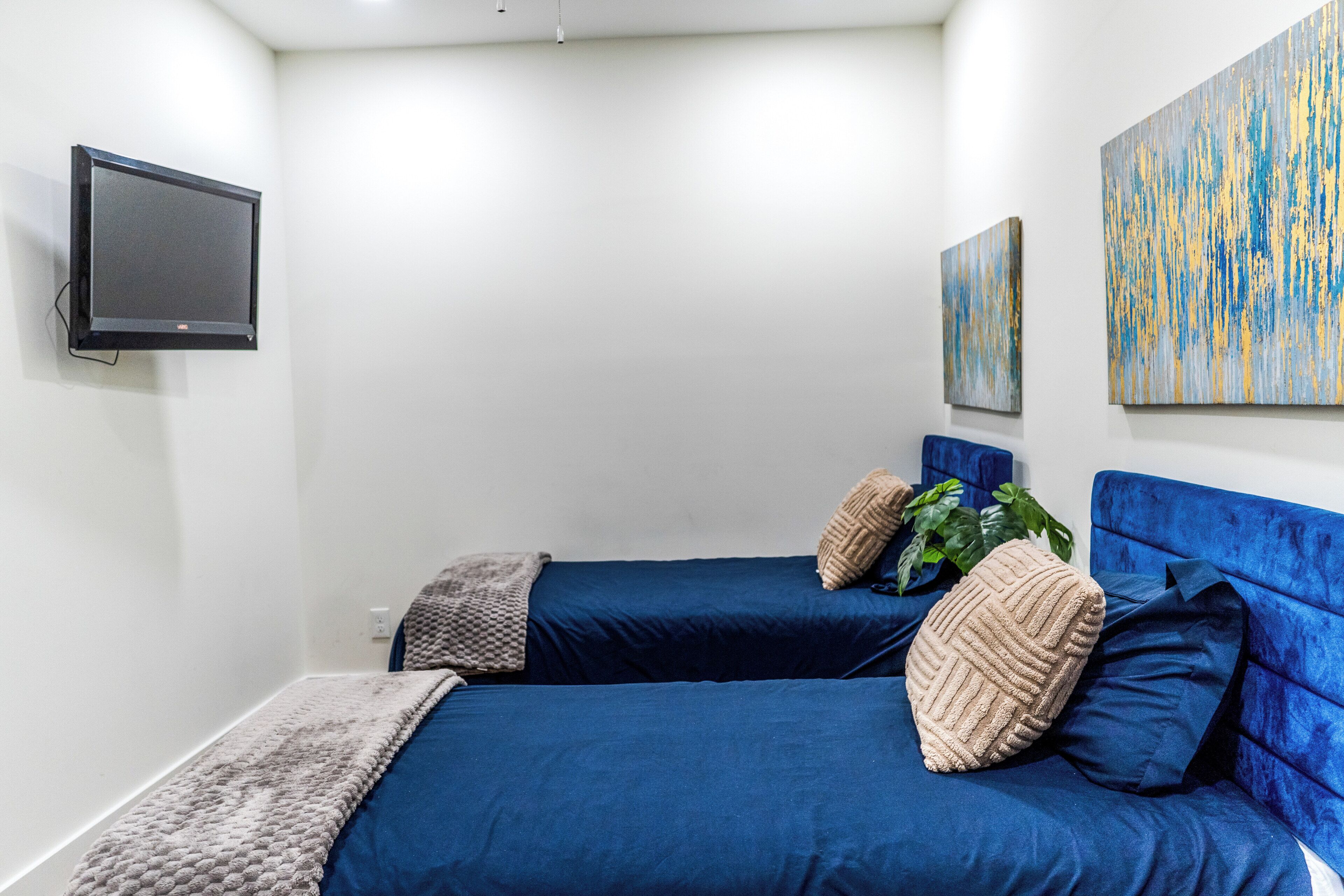 Una habitación con dos camas, un televisor de pantalla plana y obras de arte abstracto en las paredes.