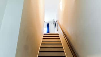 A staircase with a handrail leading to a room with a blue curtain.
