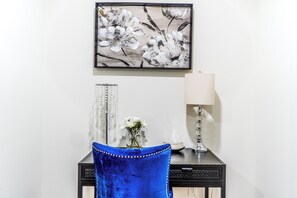 A room with a black desk, a blue chair, a vase with flowers, a lamp, and a framed artwork on the wall. - Atlanta Luxe Stay (Atlanta)