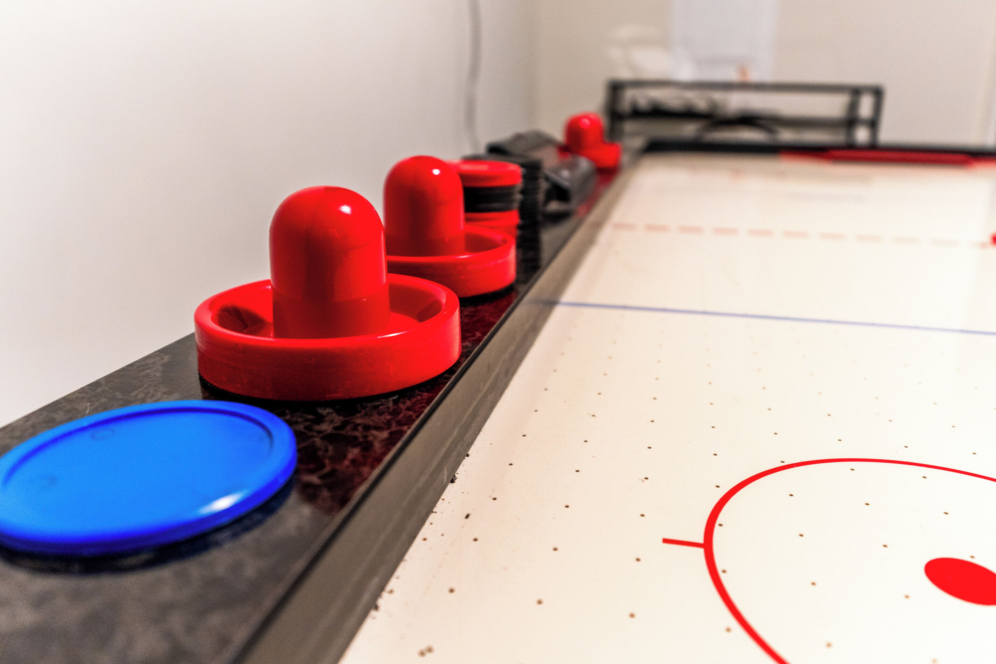 Primer plano de una mesa de shuffleboard con discos rojos y azules.
