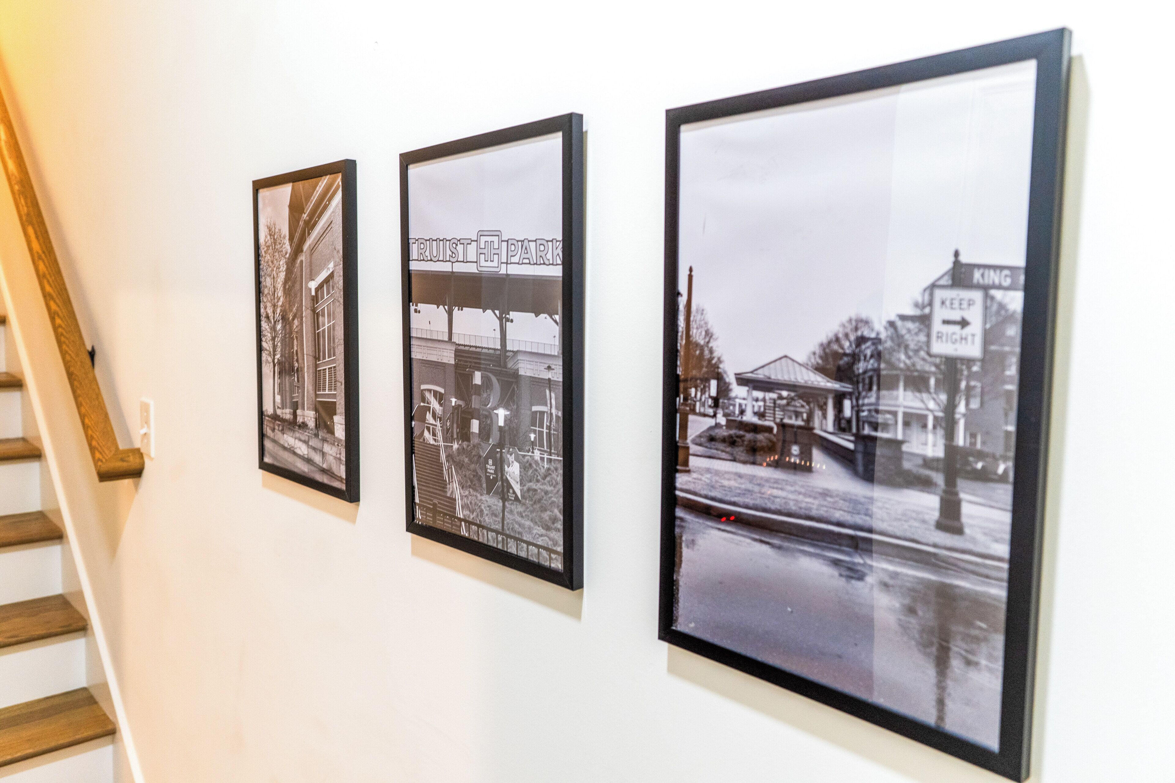Trois photographies en noir et blanc, accrochées au mur, représentent des scènes urbaines avec des bâtiments et des panneaux indicateurs.