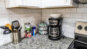 A kitchen with a coffee maker, a jar of coffee creamer, and a container of coffee pods.
