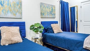A hotel room with two beds, a potted plant, and artwork on the walls.