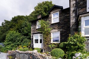 A stone house with two visible windows and a stone wall in the foreground. - Brantside, Central Ambleside, Panoramic Views (Ambleside)