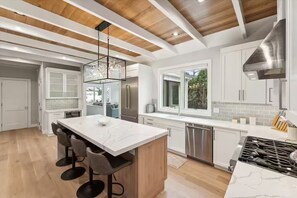 A modern kitchen with a central island, stainless steel appliances, and a view to the outside. - Spacious 4-bedroom house in tranquil Hampton Bays with pool.Close to beach (Hampton Bays)