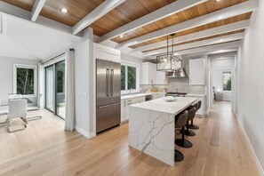 A modern kitchen with a central island, stainless steel appliances, and a wooden ceiling. - Spacious 4-bedroom house in tranquil Hampton Bays with pool.Close to beach (Hampton Bays)