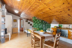 Eine gemütliche Küche mit Holzbalken, einem Esstisch mit Stühlen und einer Zierpflanze.