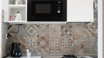 A kitchen with a microwave, a kettle, and a coffee machine.
