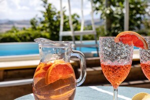 A poolside setting with a pitcher and two glasses of a pink beverage, one with a citrus slice garnish. - La Pineta Holiday Homes - Beta Apartment (Vallefoglia)