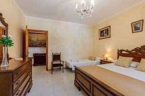 A hotel room with a bed, two bedside tables, a nightstand, a chair, a dresser, a mirror, a chandelier, and a painting on the wall. - La Pineta Holiday Homes - Beta Apartment (Vallefoglia)
