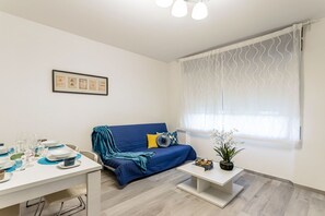 A modern living room with a sofa, a dining table, and a window with sheer curtains. - Casa Tania in Pavia With 1 Bedrooms and 1 Bathrooms (Pavia)