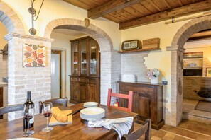 Un'area pranzo rustica con un tavolo di legno, sedie e una bottiglia di vino.