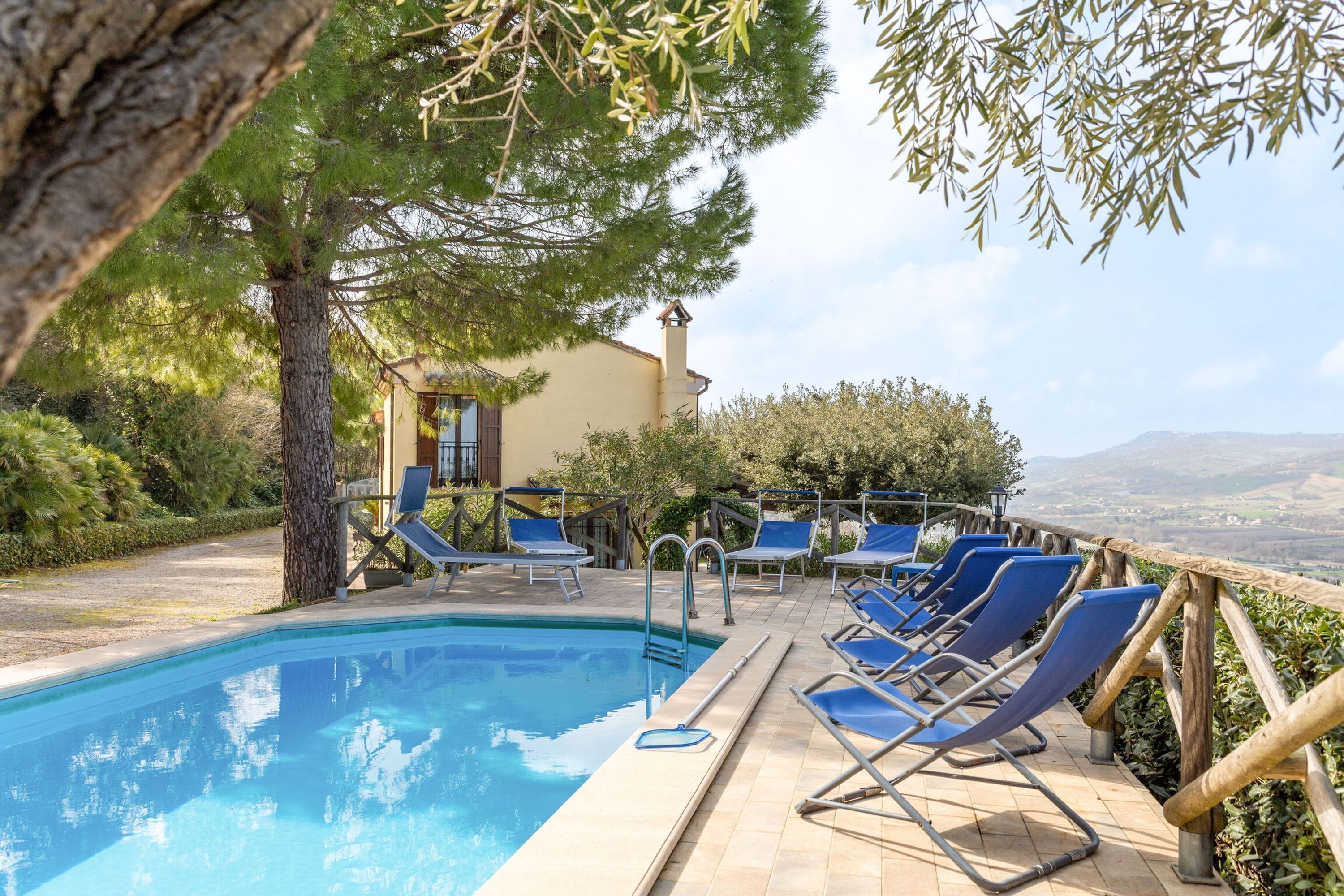 Zona piscina con lettini e vista sulla campagna.
