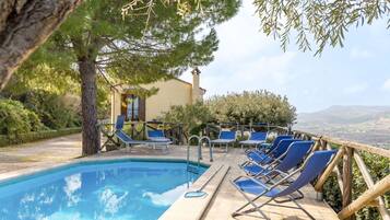 Zona piscina con lettini e vista sulla campagna.
