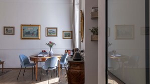 Uma sala de jantar com uma mesa redonda, cadeiras e quadros nas paredes.