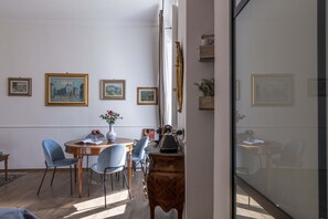 A dining area with a round table, chairs, and framed artwork on the wall. - Maison D Alice in Firenze (Florence)