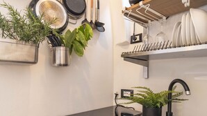 Cozinha com bancada, pia, fogão e diversos utensílios.