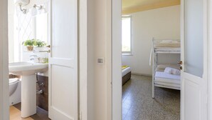 Een kamer met een stapelbed, een wastafel en een raam.