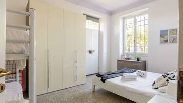 A bedroom with a bed, a dresser, a window with a view, and a wardrobe.