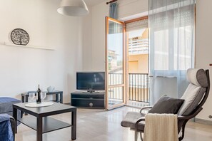 A modern living room with a flat-screen TV, a dining table, a sofa, and a chair. - Casa Acquamarina in Porto Recanati (Porto Recanati)
