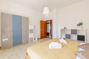 A bedroom with a bed, a wardrobe, a small table, a shelf with decorative items, and a door leading to another room. - Casa Acquamarina in Porto Recanati (Porto Recanati)