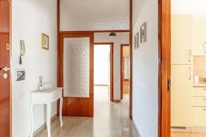 A hallway with a wooden door, a white console table with a bottle and reed diffuser, and a mirror on the wall. - Casa Acquamarina in Porto Recanati (Porto Recanati)