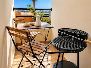 Ein Balkon mit Tisch, Stühlen, einem Grill und Blick auf die Stadt.