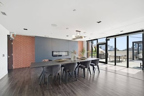 A modern kitchen with a large island, dark wood flooring, and a view of the city through large windows. - Sleek 2BR Condo | City View | Pool, Gym & Bowling (Kitchener)