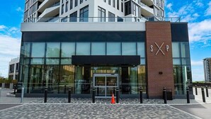 Un edificio moderno con fachada de vidrio, un llamativo letrero 'SXP' y pavimento con diseño.