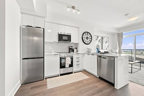 A modern kitchen with stainless steel appliances, white cabinetry, and a large window offering a city view. - Sleek 2BR Condo | City View | Pool, Gym & Bowling (Kitchener)