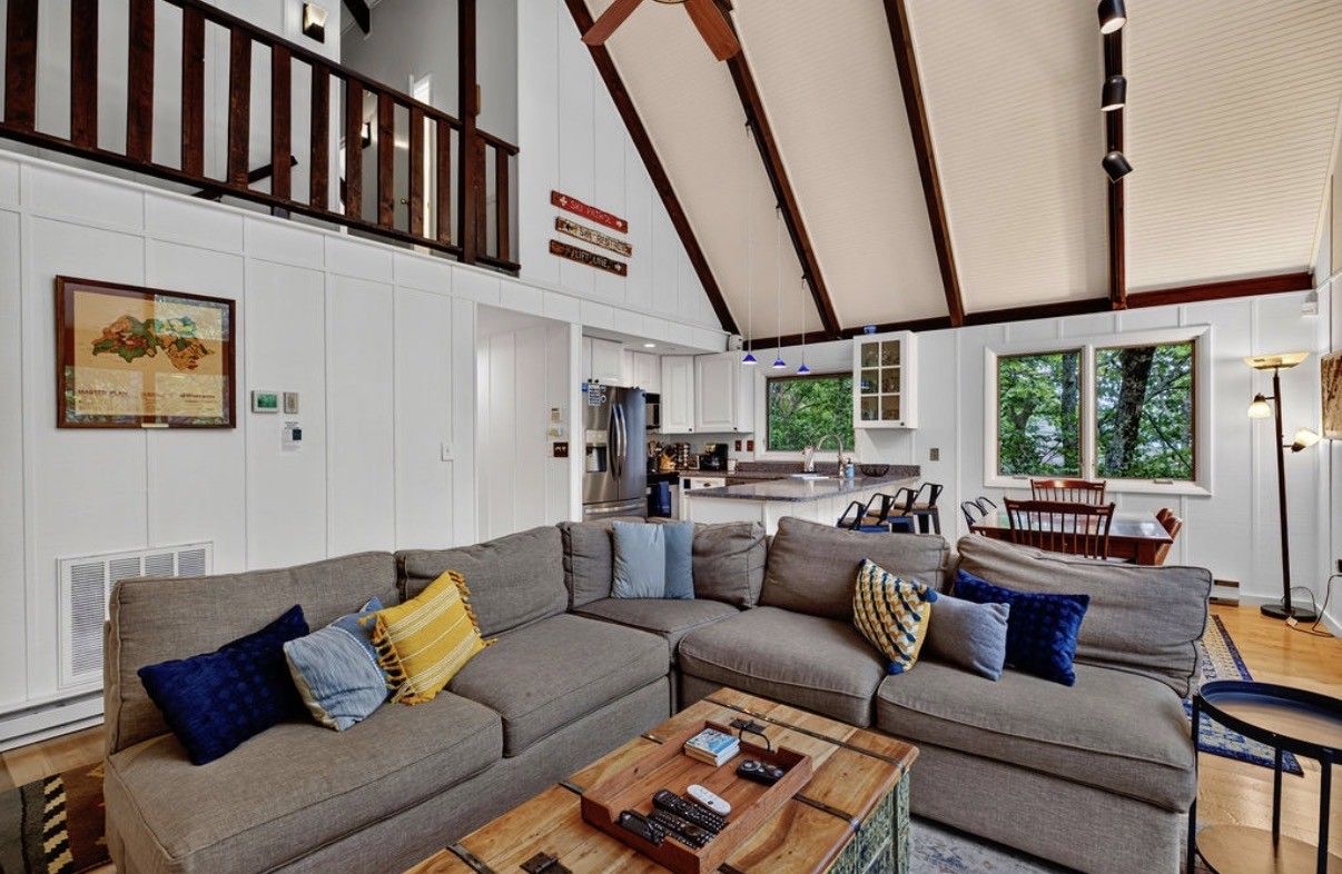 A spacious living room with a large sectional sofa, a wooden coffee table, and a dining area with a table and chairs.