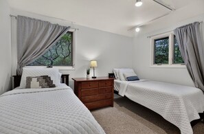 Une chambre avec deux lits, une commode et une fenêtre avec des rideaux.
