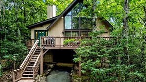 A cabin with a wooden deck, a staircase, and a view of a forested area. - Charming Wintergreen A-Frame-Walk to Slopes & Trails-Fireplace, Deck + Sleeps 8 (Wintergreen Resort)