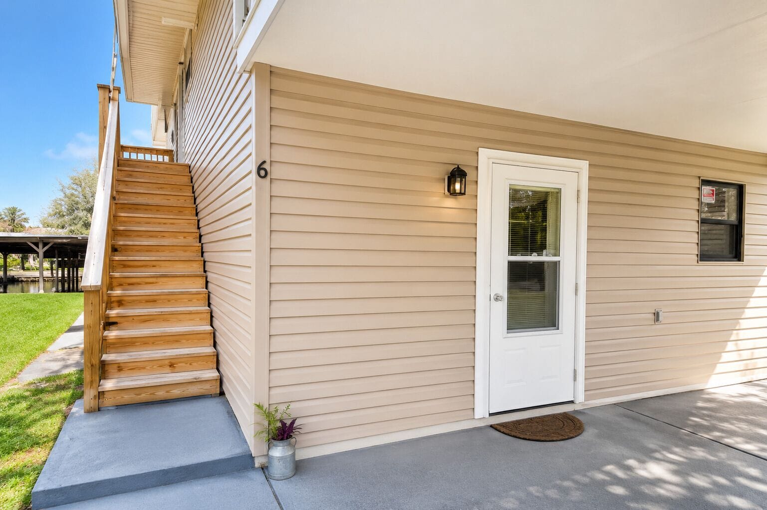 A two-story house with a wooden staircase, a white front door, and a small porch area.