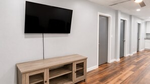 A modern living room with a flat-screen TV mounted on the wall, a wooden console table, and a hardwood floor.